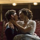 Ein Paar in inniger Umarmung in einem leeren Theater, sitzt vertraut, warmes Licht im Hintergrund.