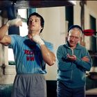 Text auf dem T-Shirt: "WIN 'ROCKY' WIN". Ein Boxer trainiert mit einem Punchingball, ein älterer Mann beobachtet ihn.