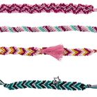 Vier bunte Freundschaftsarmbänder mit Zickzack-Mustern und Quasten, eines mit einem Sternanhänger.