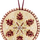 Kreisförmige Holzscheibe, darauf rotes, blumenartiges Stickmuster mit goldenen Akzenten und weißem Detail.