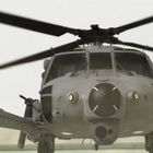 Ein Mann läuft, während ein großer Hubschrauber mit rotierenden Rotorblättern auf einer Plattform steht.