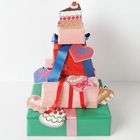 Herz-Etikett mit pinker Schleife, farbenfrohe Geschenke in verschiedenen Lagen, verziert mit Tortenbildern.