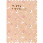 „HAPPY BIRTHDAY“ in goldener Schrift. Hintergrund: Pastellrosa mit weiß-rotem Blumenmuster und gewelltem Rand.