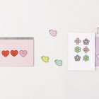 Drei Herzen auf einer Karte, bunte Blumen- und Vogeldekorationen, lila Umschlag.