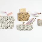 Vier Täschchen mit floralen Mustern, bunte Radiergummis und Bleistifte auf hellem Hintergrund.