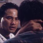 Ein Mann schaut ernsthaft einen anderen Mann an und hält dessen Nacken fest. Die Szene wirkt emotional intensiv.