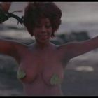 Es gibt keinen Text im Bild. Eine Frau tanzt teilweise unbekleidet in einer natürlichen Umgebung.