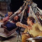 Mehrere Personen entspannen in bunten Hängematten, eine davon ist eingenickt. Es herrscht eine entspannte Atmosphäre.