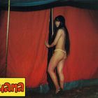 Text "Luana" in einem gelben Kasten. Eine Frau mit langen Haaren steht vor einem roten Zelt.