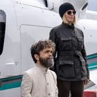 Zwei Personen stehen vor einem weißen Flugzeug mit türkisfarbenen Streifen. Eine Person trägt einen Bart, die andere eine Mütze.