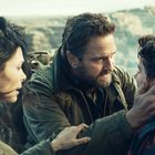 Ein Mann hält einen jüngeren Mann im Gesicht und spricht ernst. Eine Frau steht dicht daneben.