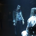 Ein Mann und ein Mädchen halten Händchen. Hintergrund mit orangefarbenem Licht, die Szene wirkt dramatisch.