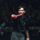 Ich kann die Person nicht identifizieren. Sie spielt Tischtennis vor einem großen Publikum in einem Stadion.