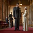 Zwei Männer stehen auf einem roten Teppich in einem opulenten Flur. Einer trägt einen Anzug, der andere eine päpstliche Robe.