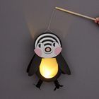 Ein Pinguin-Lampion, der von einer Hand an einem Stab gehalten wird. Der Bauch leuchtet gelblich.