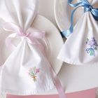 Keine Texte. Zwei Teller mit Stoffservietten, gebunden mit rosa und blauen Schleifen, darauf Blumenstickereien.