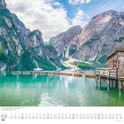 07 Juli, Montag, Dienstag. Kalenderblatt zeigt einen See mit Booten, einem Holzhaus und Bergen im Hintergrund.