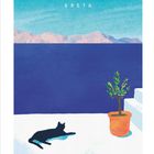 "KRETA" und "AUGUST" sind zu lesen. Eine schwarze Katze liegt in der Sonne auf einer weißen Terrasse mit Topfpflanze.