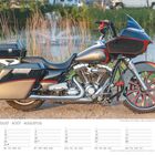 August-Kalender. Ein schwarzes Motorrad mit roten Akzenten steht vor einem See mit Schilf im Hintergrund.