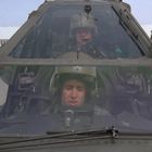 Cockpit eines Militärhubschraubers mit zwei Piloten in Helmen. Hangar im Hintergrund.