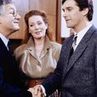 Es gibt keinen Text im Bild. Zwei Männer schütteln sich die Hand; eine Frau steht zwischen ihnen und schaut zu.