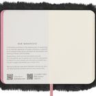 Ein offenes Notizbuch mit einer Seite Text, der das "OUR MANIFESTO" von Moleskine beschreibt. Flauschiges schwarzes Cover.