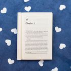 "Chapter 1" steht oben. Offenes Buch auf blauem Hintergrund, umgeben von weißen Herzformen.