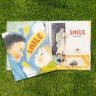 Text: „SMILE“ von Maya Shleifer. Illustration von zwei Kindern, die sich anlächeln. Im Hintergrund eine erwachsene Person.