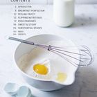 Inhaltsverzeichnis mit Kapiteln wie "Introduction" und "Breakfast Perfection". Schüssel mit Mehl, Ei und einem Schneebesen. Milchflasche im Hintergrund.