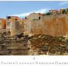 "Bonifacio", 4. Steilküste mit historischem Dorf oben, sandfarbene Gebäude, sonniger Himmel, Vegetation auf Felsen.