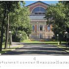 Der Text lautet "Bayreuth, Festspielhaus". Eine von Bäumen gesäumte Straße führt zu einem beeindruckenden Gebäude.