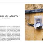"DER WECKER VON LA TOLETTA: Die Hexen-Uhrzeit?" zeigt eine alte Uhr in einem durchsichtigen Kasten an einer gelben Wand.