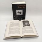 Ein Buch mit dem Titel "Was zählt ein Mensch?" von Carolin Emcke steht aufrecht hinter einem aufgeschlagenen Buch.