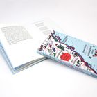 Ein Buch liegt auf einem geöffneten Buch. Der Einband zeigt eine bunte Karte mit dem Titel "James Krüss Polulaugrische Lieder".