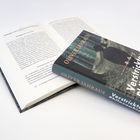 „Verstrickte Philosophie“ von Oliver Jahraus. Ein Buch liegt offen, das andere mit dem Cover nach oben darauf.