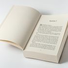 Aufgeschlagenes Buch mit Text "Kapitel 1" oben; darunter beginnt die Erzählung mit einem Dialog.