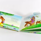 Es steht ein offenes Kinderbuch vor dir. Ein Osterhase mit bunten Eiern in einer grünen Landschaft.