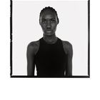 Eine Frau mit Zöpfen trägt ein dunkles Oberteil. Der Hintergrund ist weiß. Die Aufnahme hat einen Schwarzweißrahmen.