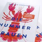 "Spiegel Bestseller" Aufkleber; Titel: "Die Hummerfrauen". Illustration eines roten Hummers. Autor: Beatrix Gerstberger.
