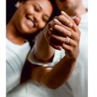 Ein lächelndes Paar hält sich an den Händen. Die Szene strahlt Nähe und Harmonie aus.