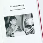 Die Texte lauten: "DIE UNBEHAUSTE" und "ÜBER DOROTHY PARKER". Eine Frau denkt nach, während sie an einem Schreibtisch schreibt.