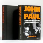 Text: "JOHN & PAUL: Eine musikalische Liebesgeschichte" von Ian Leslie. Zwei Bücher, eines mit Bild von zwei Männern.