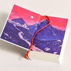 Illustration eines Berges mit pinkem Himmel und rotem Band in einem Buch.