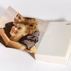 Text "HEYNE" auf einer leeren Buchseite. Links davon ein gedrucktes Bild mit zwei lächelnden Personen, die sich umarmen.