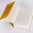 Ein Buch mit geöffnetem gelbem Einband, der Text und ein Inhaltsverzeichnis zeigt. Kapitel 1: "Die kostbaren Reste..."