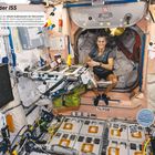 "An Bord der ISS" steht oben. Eine Frau sitzt entspannt in der Raumstation, umgeben von Ausrüstung und Gegenständen.
