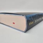 Auf einem Buchrücken steht "SUSAN CHOI", "LEUCHTSPUREN", "PIPER". Das Buch liegt geschlossen, ein rotes Stofflesezeichen sichtbar.
