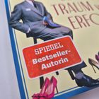 Text: "SPIEGEL Bestseller-Autorin", "TRAUM VOM ERFOLG". Cover eines Buches mit einem Mann in Anzug und verschiedenen Schuhen.