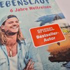 Text: „6 Jahre Weltreisen“, „SPIEGEL Bestseller-Autor“. Ein Mann mit langen Haaren lächelt, er trägt eine Kappe rückwärts.