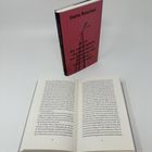 Ein Buch mit dem Titel „Es ist die Leichtigkeit, die den Herrn am Tisch von der Putfrau unterscheidet“ von Slata Roschal. Ein Exemplar steht aufrecht, ein anderes ist geöffnet.